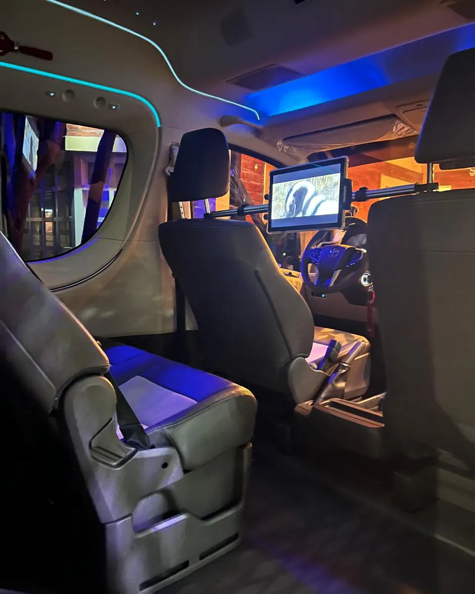 Interior de la Toyota Hiace de Traslados VIP con iluminación ambiental y pantalla multimedia