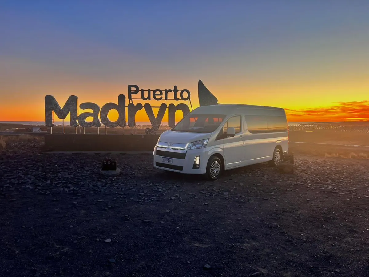 Toyota Hiace de Traslados VIP junto al cartel de Puerto Madryn al atardecer